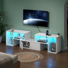 a living room with a large flat screen tv on the wall and speakers in front of it