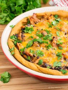 an enchilada in a red and white dish with cilantro on top