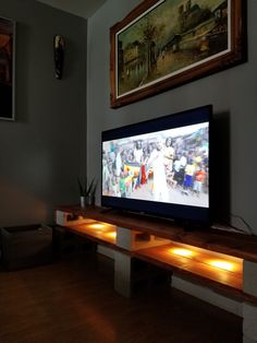 a flat screen tv sitting on top of a wooden shelf