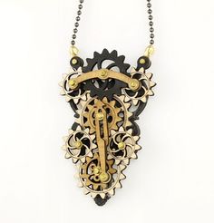 an intricate wooden necklace with gears and beads on a beaded chain hanging from a white wall