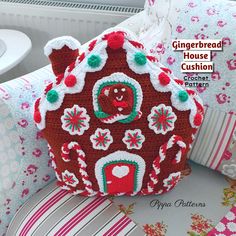 a crocheted gingerbread house cushion sitting on top of pillows