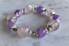 "Genuine gemstone bracelet - limited quantity, will not have any more available after this. Stunning custom, handmade bracelet with large, light rose quartz beads and slightly smaller purple kunzite beads. Silver-toned accents. Gorgeous and shiny -- really catches the light well.  Bracelet can stretch to fit your wrist. In its \"resting,\" un-stretched state, it is around 7.5 inches in circumference. Length is around 8 inches. Thickness of round beads is about 13 mm or 1/2 of an inch. \"Rose Quartz purifies and opens the heart at all levels to promote love, self-love, friendship, deep inner healing and feelings of peace. Calming and reassuring, it helps to comfort in times of grief. Rose Quartz dispels negativity and protects against environmental pollution, replacing it with loving vibes. Hand-strung Pink Amethyst Bracelets, Hand-strung Pink Amethyst Bracelet, Pink Amethyst Round Beads Crystal Bracelet, Pink Amethyst Crystal Bracelet With Round Beads, Pink Amethyst Beaded Bracelets For Gift, Pink Amethyst Round Beads Bracelet, Pink Hand-strung Amethyst Jewelry, Spiritual Pink Amethyst Beaded Bracelet, Pink Amethyst Crystal Bracelet With Gemstone Beads