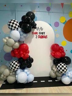 balloon arch with two fast 2 balloons and checkerboard design in front of blue wall