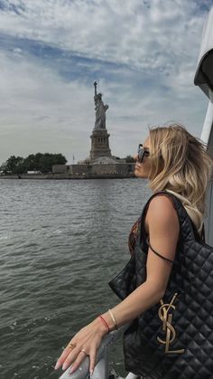 a woman on a boat looking at the statue of liberty