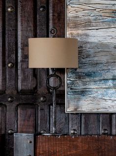 a lamp sitting on top of a wooden table next to a wall with metal rivets