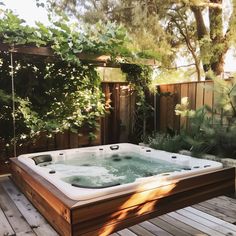 a hot tub sitting on top of a wooden deck next to a lush green tree