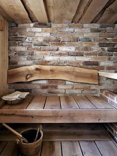 a wooden bench sitting in front of a brick wall next to a bucket and broom