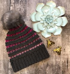 a crocheted hat with a flower next to it on top of a wooden table