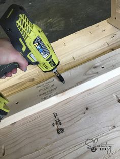 a person using a cordless drill to screw holes in plywood planks that are being built