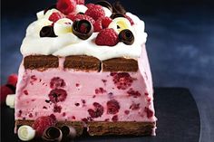 a piece of cake with raspberries and whipped cream on top is sitting on a black plate