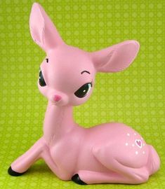 a pink toy deer sitting on top of a green surface