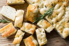 bread with herbs and garlic on a wooden cutting board next to some slices of bread