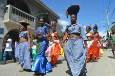 a group of women are walking down the street in colorful dresses and headpieces