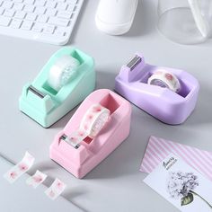 three different types of tape dispensers on a white table next to a keyboard