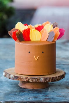 a cake decorated to look like a bird with feathers on it's head is sitting on a wooden stand