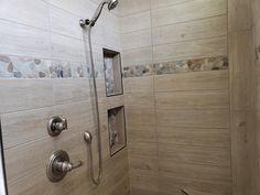 a walk in shower sitting next to a tiled wall and wooden floored walls on either side of the shower head