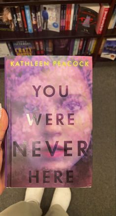 someone holding up a book with the title you were never here in front of them