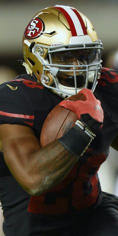 a close up of a football player with a helmet on holding a ball in his hands