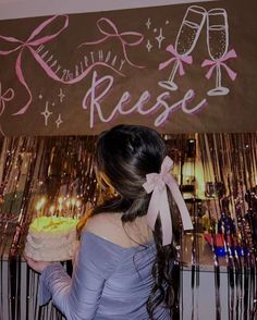 a woman holding a cake in front of a sign