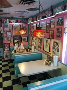 a woman sitting at a table in a diner with pictures on the wall behind her