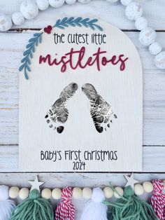 two baby's first christmas ornament hanging on a white wooden wall with ornaments around it