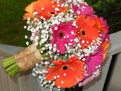 a bouquet of colorful flowers sitting on top of a wooden table next to a fence