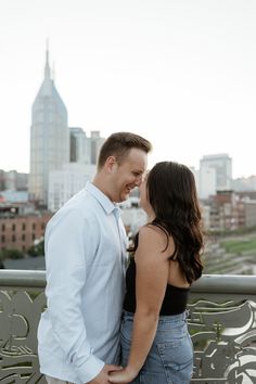 a man and woman standing next to each other in front of a cityscape