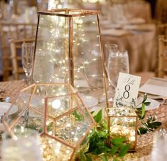 the centerpieces are set up on top of each other with candles and greenery