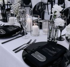 the table is set with white flowers and black plates