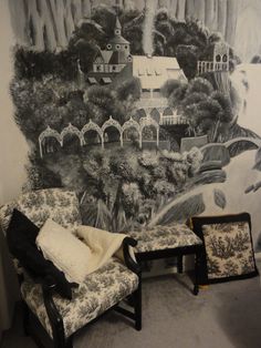 a living room with a large mural on the wall and two chairs in front of it