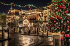 a christmas tree is lit up in the middle of a city street with buildings and lights all around it