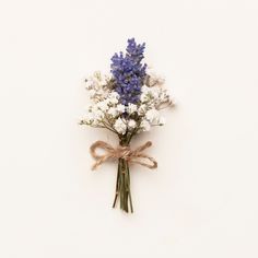 a bunch of white and blue flowers tied up to a ribbon on a white wall