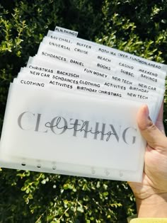 someone is holding up several clear plastic tags with the word clothing printed on them in front of some trees