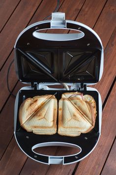 two sandwiches are being cooked in an electric sandwich maker