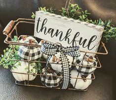 a basket filled with white pumpkins sitting on top of a black leather couch next to a sign that says thank