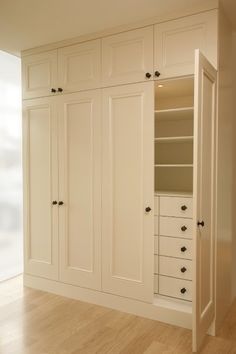 an empty room with white cabinets and wood floors