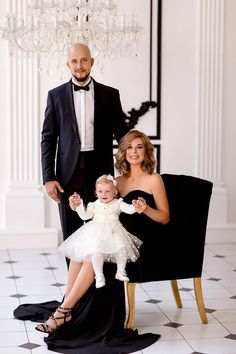 a man in a tuxedo poses with his wife and baby