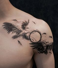 a man's chest with an eagle tattoo on his left shoulder and wings flying around it