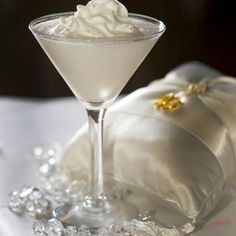 a glass filled with white liquid sitting on top of a table next to a pillow