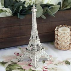 a small model of the eiffel tower sitting on a table next to flowers