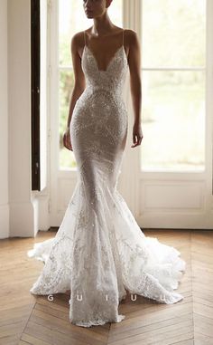 a woman in a white wedding dress standing on a wooden floor next to a window