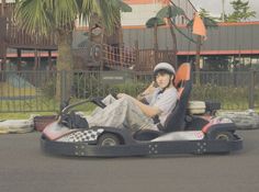 a young man is sitting on a bumper car in the middle of an empty parking lot