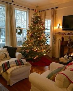 a living room with a christmas tree and couches in front of a fire place