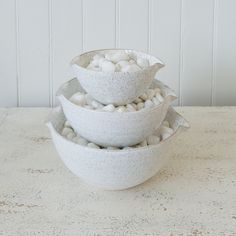 three bowls are stacked on top of each other with white rocks in them and one bowl is filled with pebbles