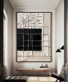 a black and white abstract painting hanging on the wall above a wooden table in a living room