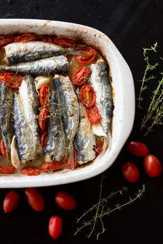 some fish are in a white dish with tomatoes