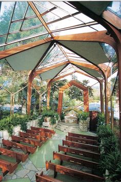 the inside of a building with wooden benches and plants in pots on either side of the walkway