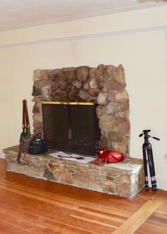 a living room with a stone fireplace and hard wood flooring