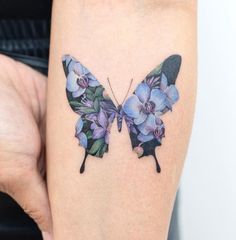 a woman's arm with a butterfly and flowers tattoo on the back of her leg