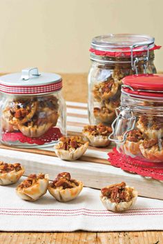 some food is sitting in small bowls on a table next to glass jars with lids